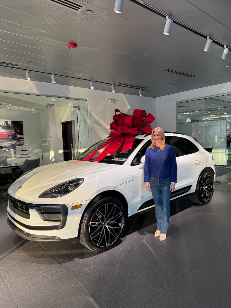 Happy customer with a new white Porsche Macan at the dealership